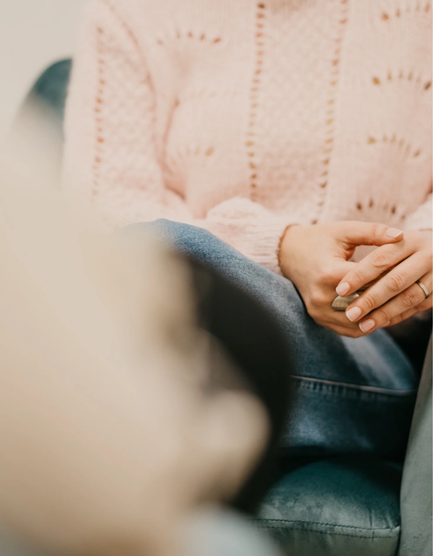 A woman's hands, resting calmly on her knees, during a therapy session