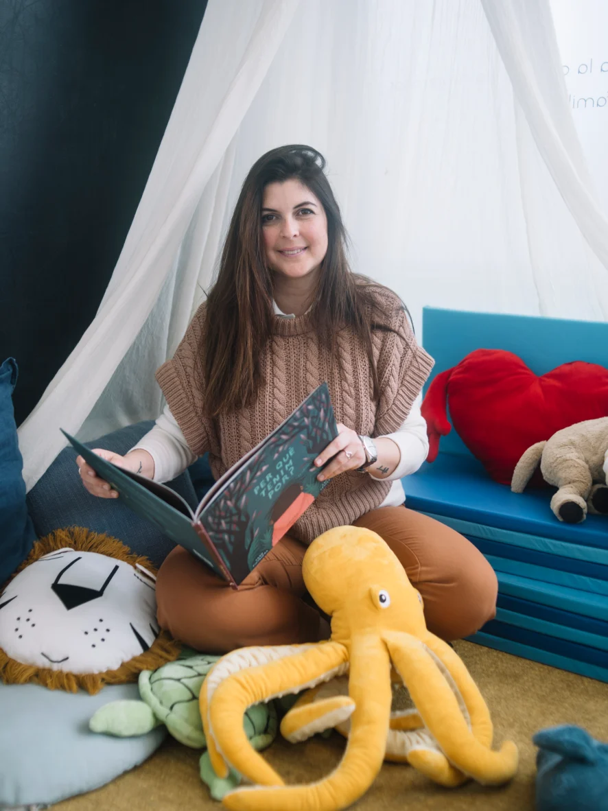 A psychologist from the team holding a storybook in the play area of the El Masnou practice